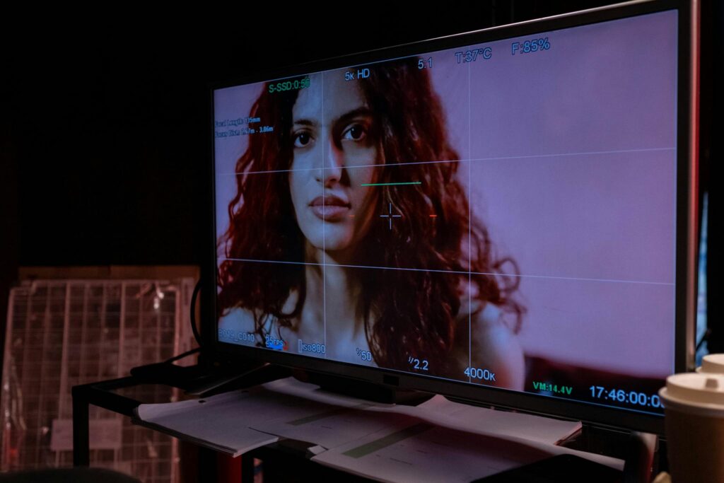 A monitor displays a woman's portrait with technical overlay, indoors.